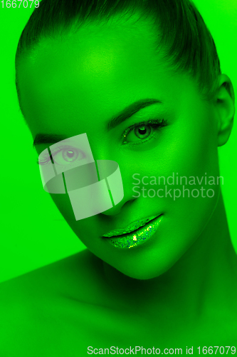 Image of Handsome woman\'s portrait isolated on green studio background in neon light, monochrome