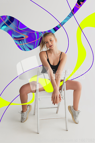 Image of Stylish young girl\'s portrait on white studio background with bright illustrated lines of fluid neoned colors. Having fun, happy, full length