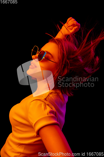 Image of Caucasian woman\'s portrait isolated on black studio background in multicolored neon light