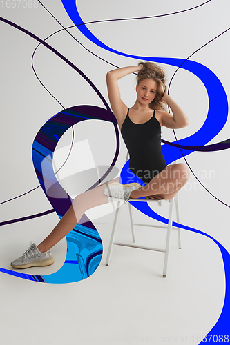 Image of Stylish young girl\'s portrait on white studio background with bright illustrated lines of fluid neoned colors. Having fun, happy, full length