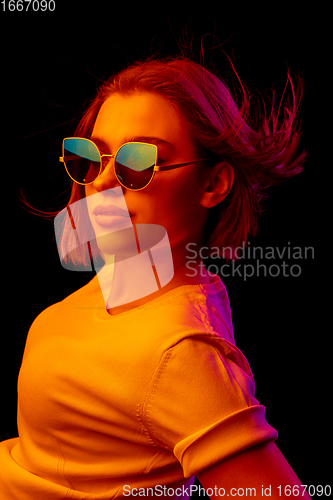 Image of Caucasian woman\'s portrait isolated on black studio background in multicolored neon light