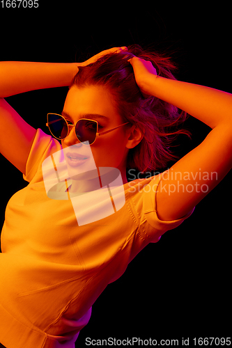 Image of Caucasian woman\'s portrait isolated on black studio background in multicolored neon light