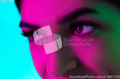 Image of Close up beautiful woman\'s eyes isolated on blue studio background in multicolored neon light