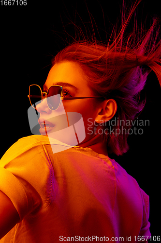 Image of Caucasian woman\'s portrait isolated on black studio background in multicolored neon light