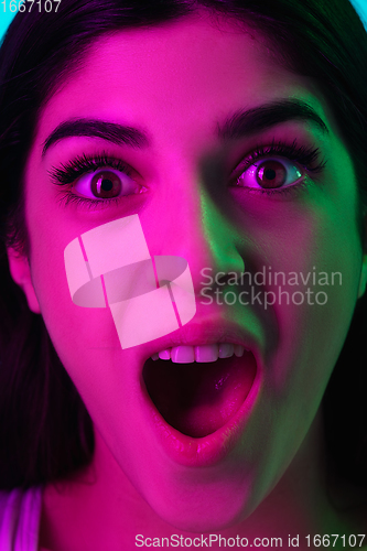 Image of Brunette beautiful woman\'s portrait isolated on blue studio background in multicolored neon light