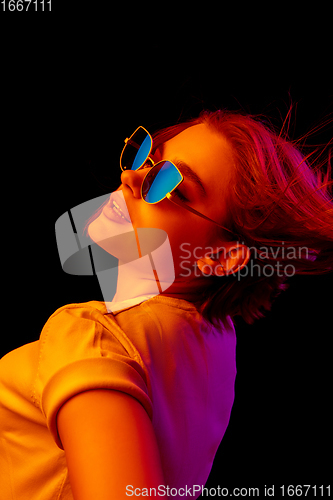 Image of Caucasian woman\'s portrait isolated on black studio background in multicolored neon light