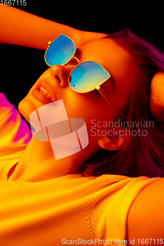 Image of Caucasian woman\'s portrait isolated on black studio background in multicolored neon light