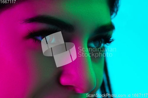 Image of Close up beautiful woman\'s eyes isolated on blue studio background in multicolored neon light