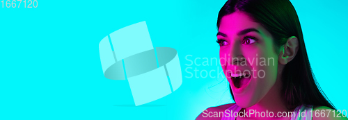 Image of Brunette beautiful woman\'s portrait isolated on blue studio background in multicolored neon light