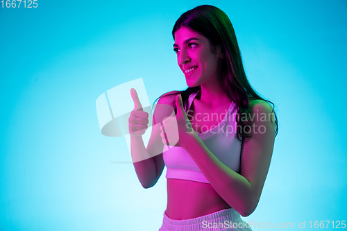 Image of Brunette beautiful woman\'s portrait isolated on blue studio background in multicolored neon light