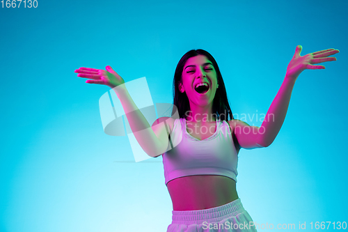 Image of Brunette beautiful woman\'s portrait isolated on blue studio background in multicolored neon light
