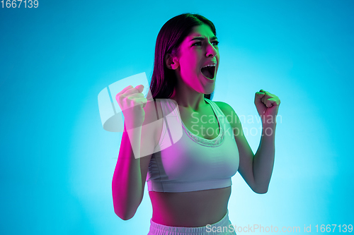 Image of Brunette beautiful woman\'s portrait isolated on blue studio background in multicolored neon light