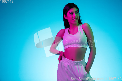 Image of Brunette beautiful woman\'s portrait isolated on blue studio background in multicolored neon light