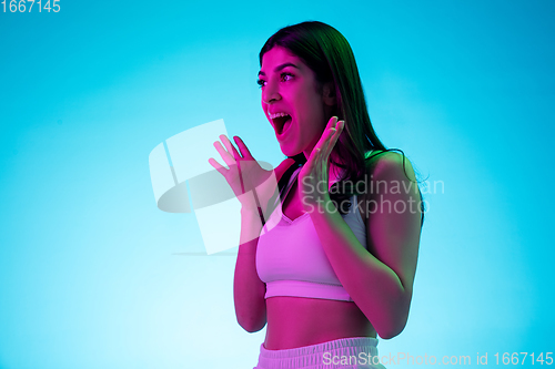 Image of Brunette beautiful woman\'s portrait isolated on blue studio background in multicolored neon light