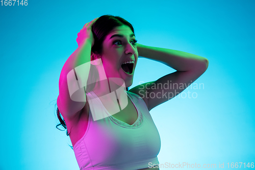 Image of Brunette beautiful woman\'s portrait isolated on blue studio background in multicolored neon light