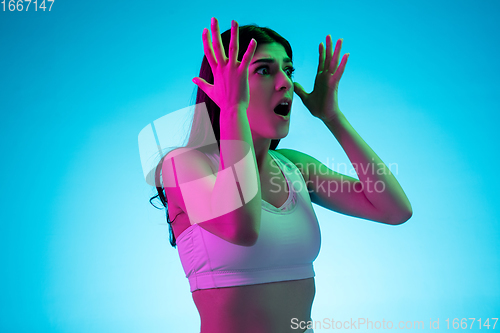Image of Brunette beautiful woman\'s portrait isolated on blue studio background in multicolored neon light