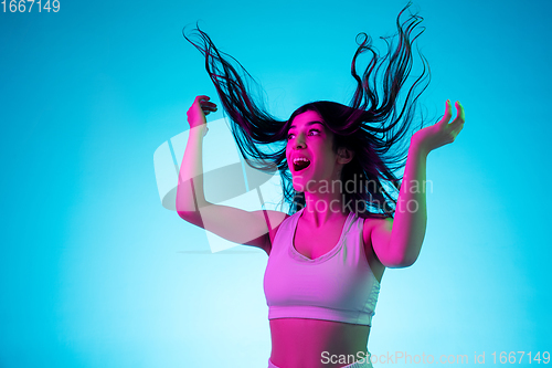 Image of Brunette beautiful woman\'s portrait isolated on blue studio background in multicolored neon light