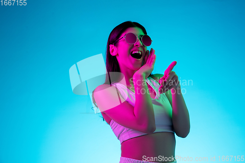 Image of Brunette beautiful woman\'s portrait isolated on blue studio background in multicolored neon light