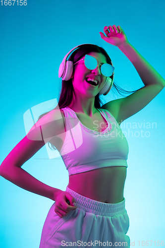 Image of Brunette beautiful woman\'s portrait isolated on blue studio background in multicolored neon light