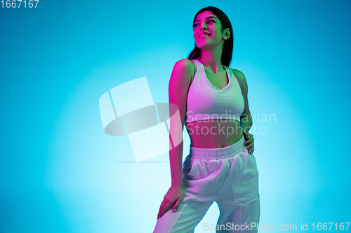 Image of Brunette beautiful woman\'s portrait isolated on blue studio background in multicolored neon light