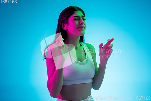 Image of Brunette beautiful woman\'s portrait isolated on blue studio background in multicolored neon light