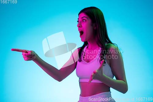 Image of Brunette beautiful woman\'s portrait isolated on blue studio background in multicolored neon light