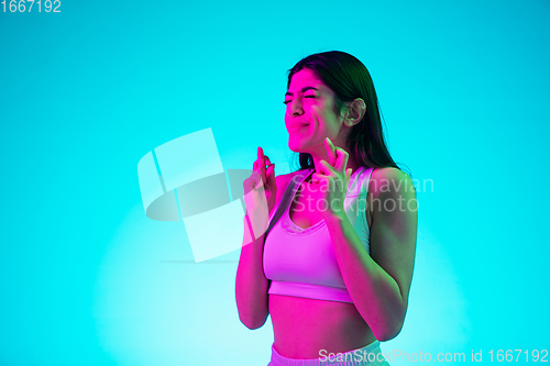 Image of Brunette beautiful woman\'s portrait isolated on blue studio background in multicolored neon light