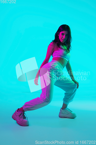 Image of Brunette beautiful woman\'s portrait isolated on blue studio background in multicolored neon light