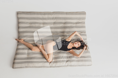 Image of Top view beautiful young woman\'s portrait isolated on striped mattress studio background. Having fun, happy, full length