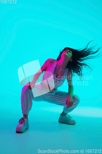 Image of Brunette beautiful woman\'s portrait isolated on blue studio background in multicolored neon light