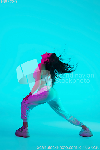 Image of Brunette beautiful woman\'s portrait isolated on blue studio background in multicolored neon light