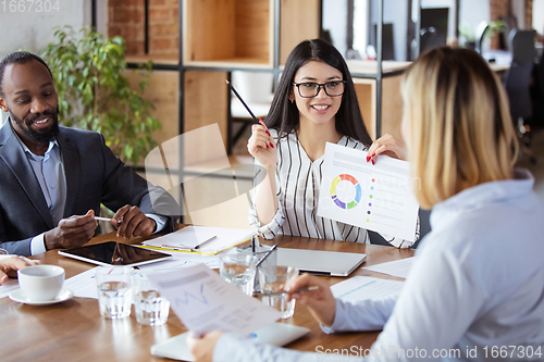 Image of Diverse group of co-workers having casual discussion in office. Executives during friendly discussion, month reporting, creative meeting