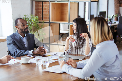 Image of Diverse group of co-workers having casual discussion in office. Executives during friendly discussion, month reporting, creative meeting