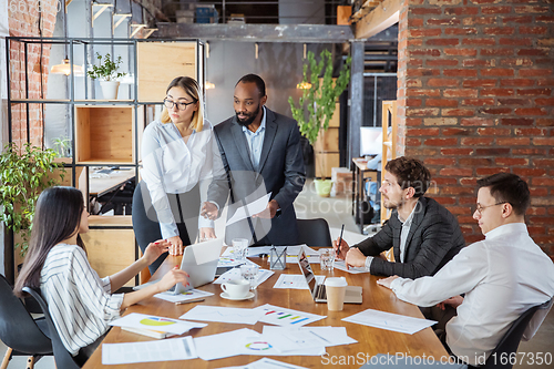 Image of Diverse group of co-workers having casual discussion in office. Executives during friendly discussion, month reporting, creative meeting