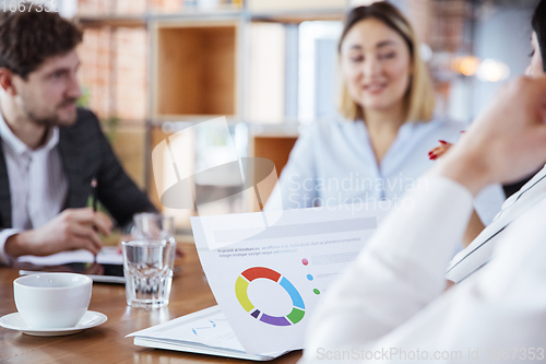 Image of Diverse group of co-workers having casual discussion in office. Executives during friendly discussion, month reporting, creative meeting. Focused on graphs.