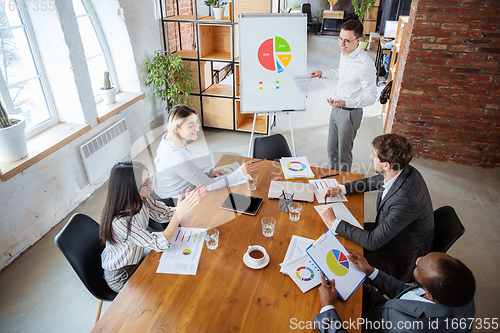 Image of Diverse group of co-workers having casual discussion in office. Executives during friendly discussion, month reporting, creative meeting. Top view.