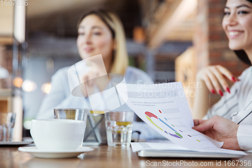 Image of Diverse group of co-workers having casual discussion in office. Executives during friendly discussion, month reporting, creative meeting. Focus on graphs.