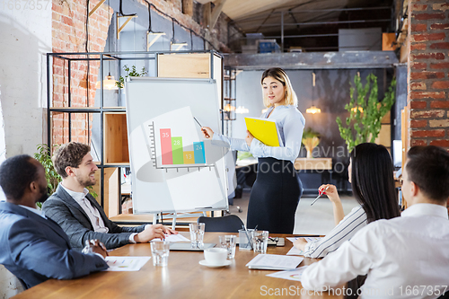 Image of Diverse group of co-workers having casual discussion in office. Executives during friendly discussion, month reporting, creative meeting