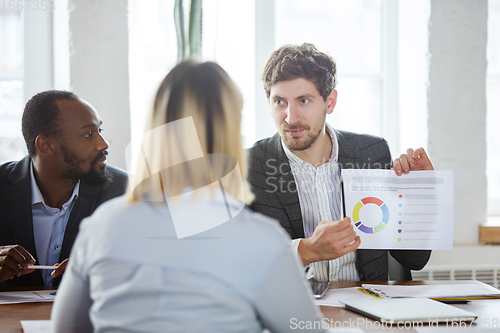 Image of Diverse group of co-workers having casual discussion in office. Executives during friendly discussion, month reporting, creative meeting