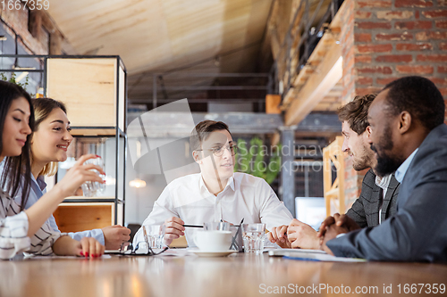 Image of Diverse group of co-workers having casual discussion in office. Executives during friendly discussion, month reporting, creative meeting