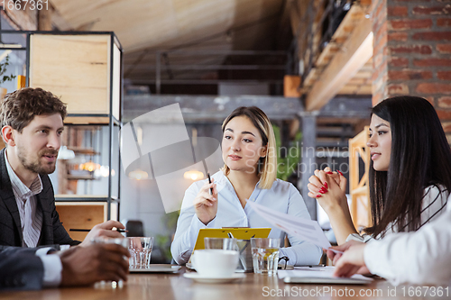 Image of Diverse group of co-workers having casual discussion in office. Executives during friendly discussion, month reporting, creative meeting