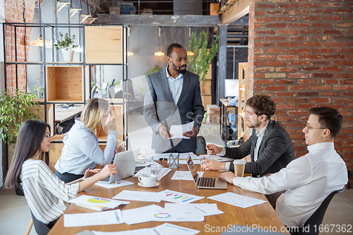 Image of Diverse group of co-workers having casual discussion in office. Executives during friendly discussion, month reporting, creative meeting