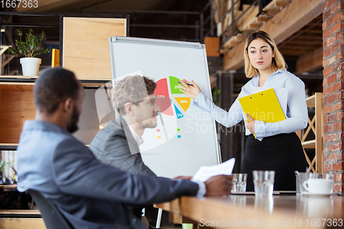 Image of Diverse group of co-workers having casual discussion in office. Executives during friendly discussion, month reporting, creative meeting