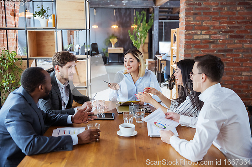 Image of Diverse group of co-workers having casual discussion in office. Executives during friendly discussion, month reporting, creative meeting