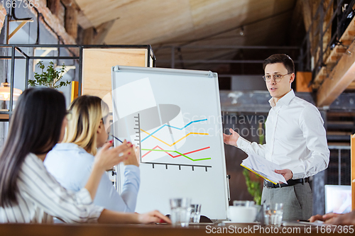 Image of Diverse group of co-workers having casual discussion in office. Executives during friendly discussion, month reporting, creative meeting