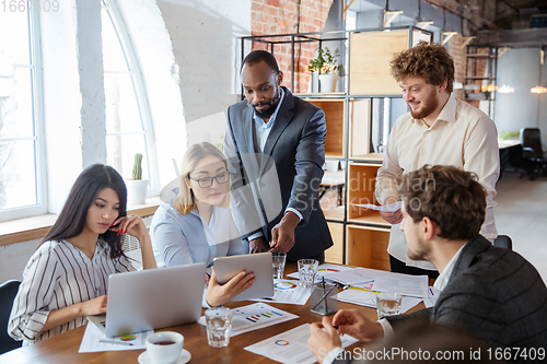 Image of Diverse group of co-workers having casual discussion in office. Executives during friendly discussion, month reporting, creative meeting