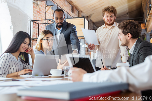 Image of Diverse group of co-workers having casual discussion in office. Executives during friendly discussion, month reporting, creative meeting