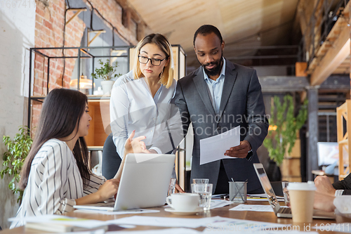 Image of Diverse group of co-workers having casual discussion in office. Executives during friendly discussion, month reporting, creative meeting