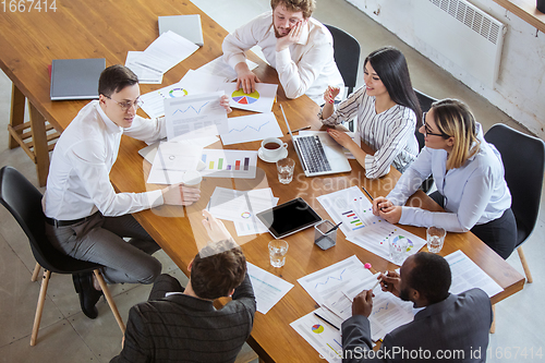 Image of Diverse group of co-workers having casual discussion in office. Executives during friendly discussion, month reporting, creative meeting. Top view.