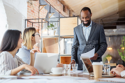 Image of Diverse group of co-workers having casual discussion in office. Executives during friendly discussion, month reporting, creative meeting